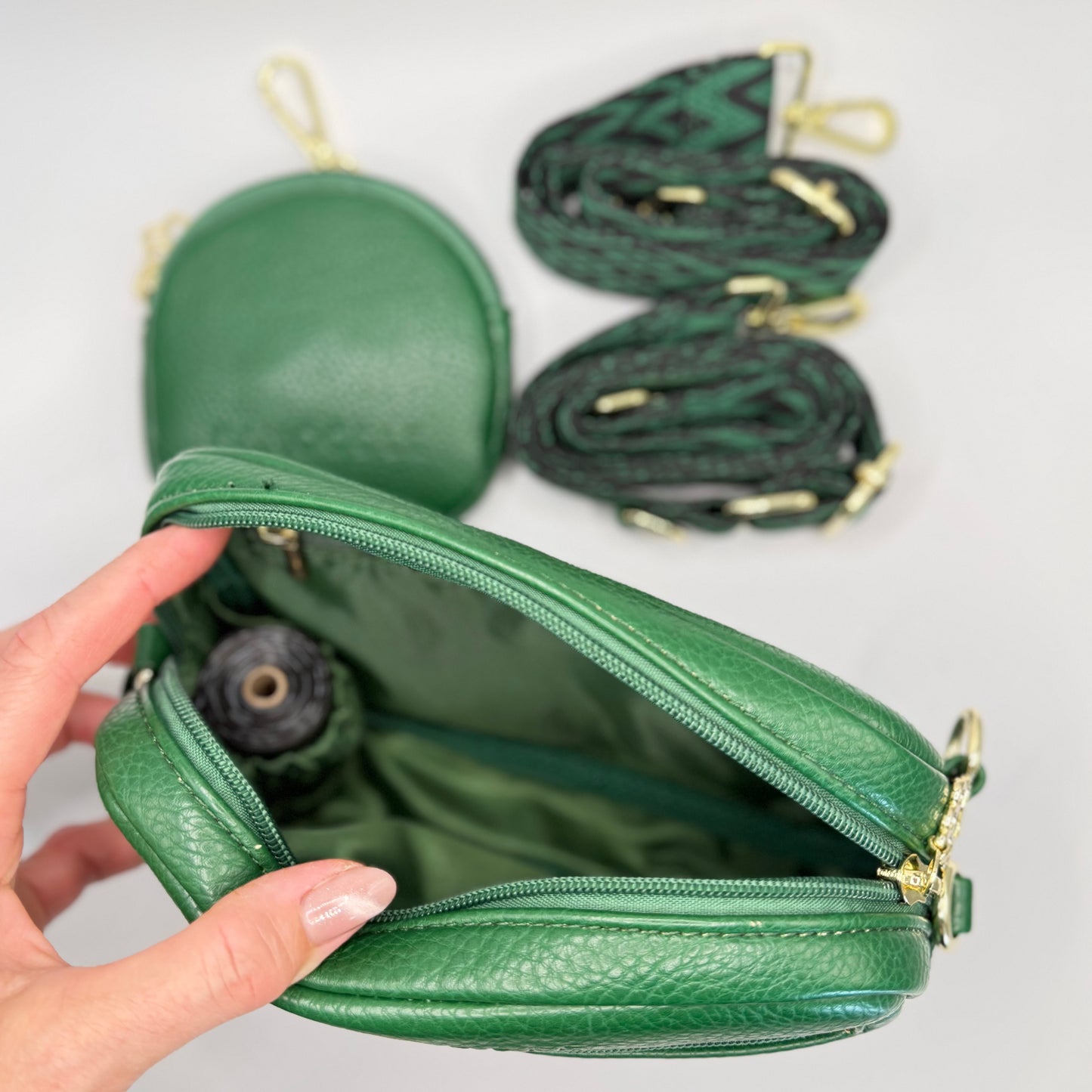 Green Dog Walking Bag with a hand opening it, background with additional green Treats bag  and bag straps